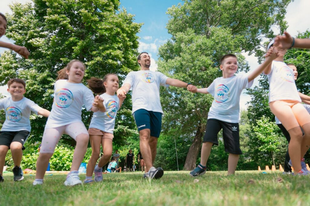 pexels photo 25748895 Group of joyful children playing outdoors with an instructor in a sunny park.