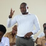 Teacher interacting with high school students in a classroom setting.