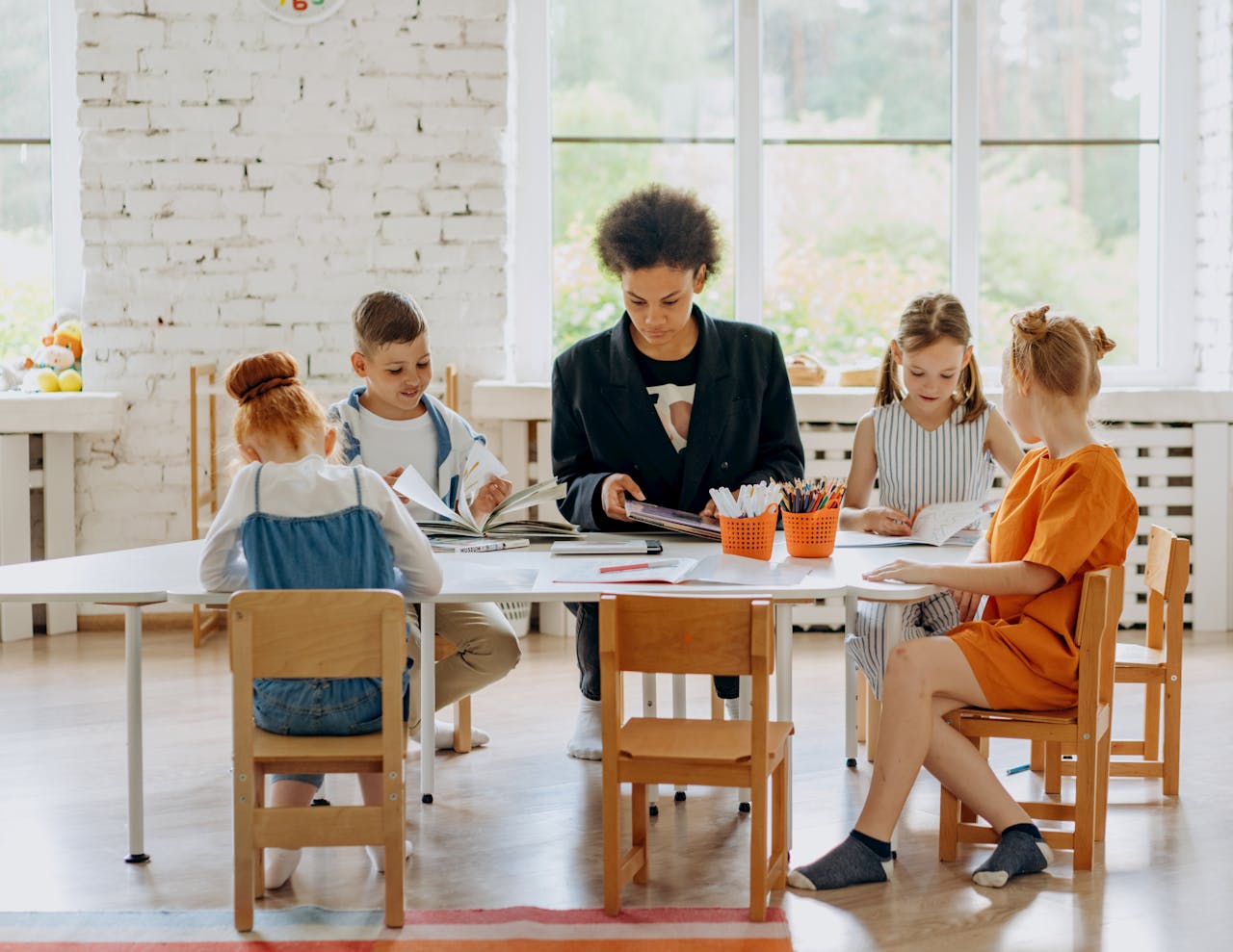 The Classroom Energy You Can't See Children learning with a teacher around a table in a bright classroom setting.